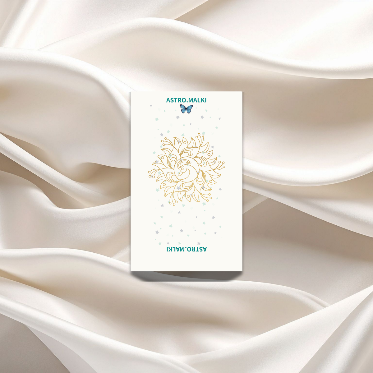 Astro Malki premium physical card deck back view featuring a gold mandala logo resting on luxury cream silk fabric.